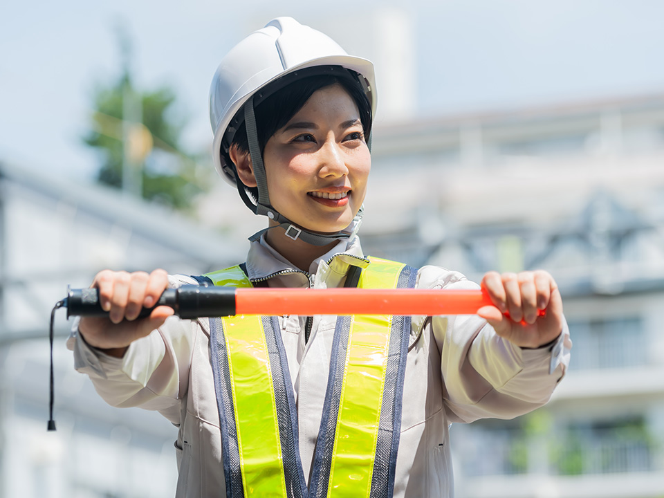 工事現場で誘導棒を掲げる女性警備員